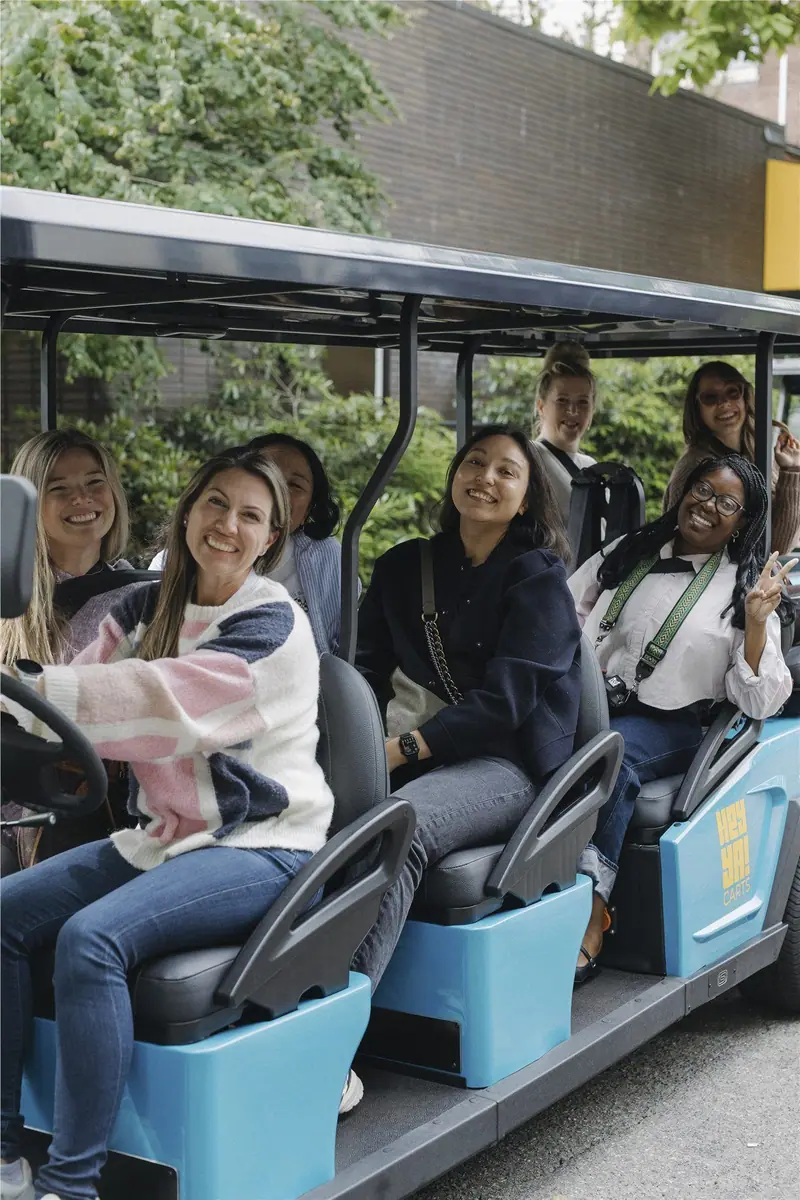 Friends smiling together aboard a HeyYa cart