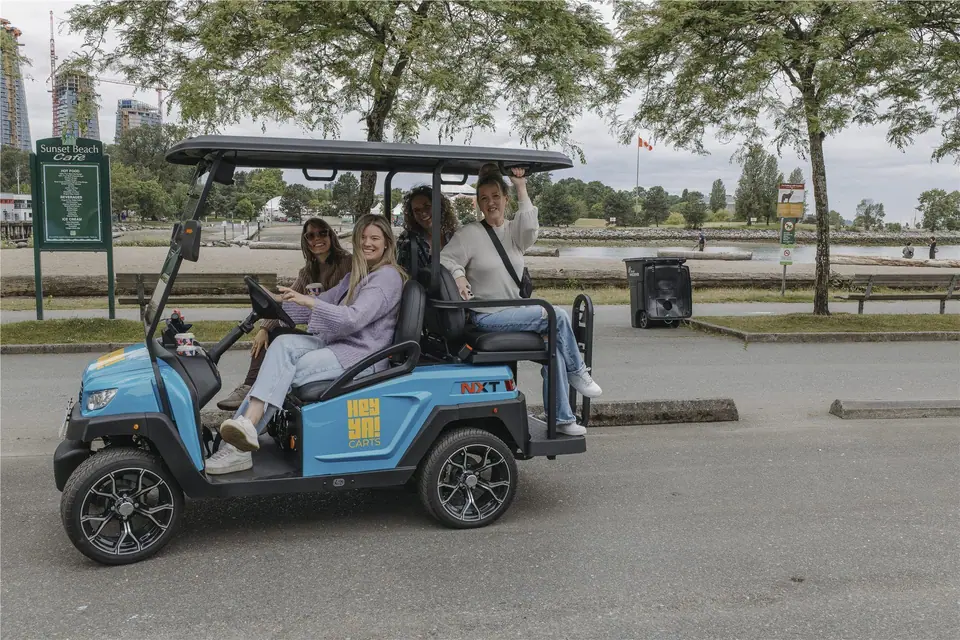 Four friends riding a HeyYa cart past Sunset Beach in Vancouver